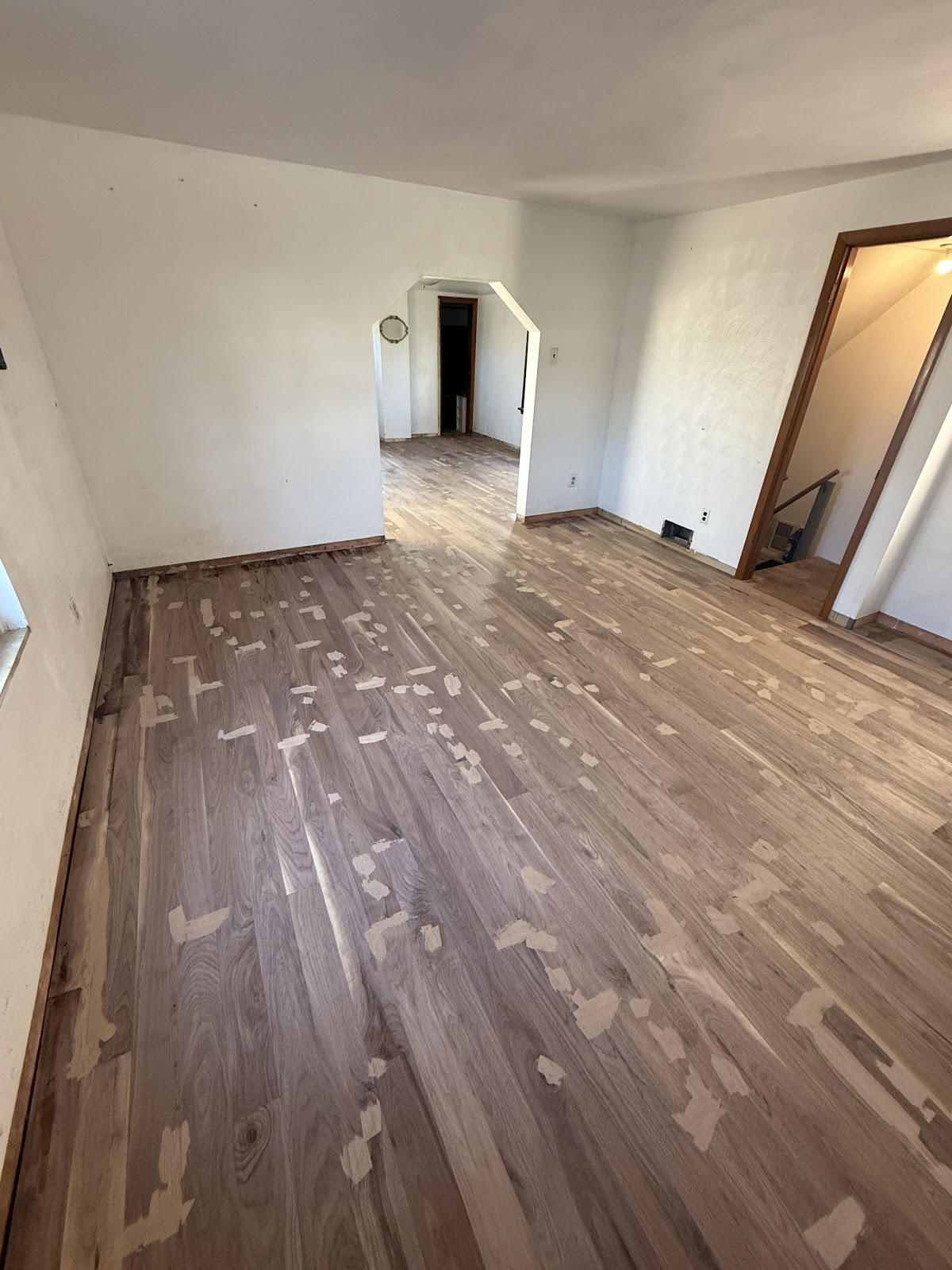 A newly installed walnut hardwood floor with wood filler patches, before final sanding